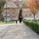 A couple jogging together in an urban park surrounded by greenery and houses.